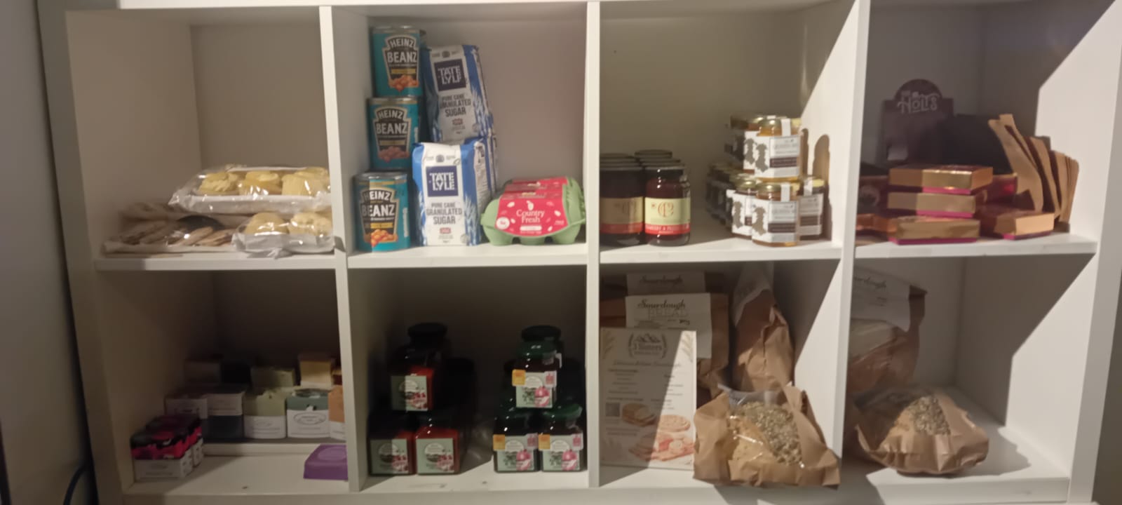 Stocked shelves at the community shop with pantry essentials, eggs, jams and bread